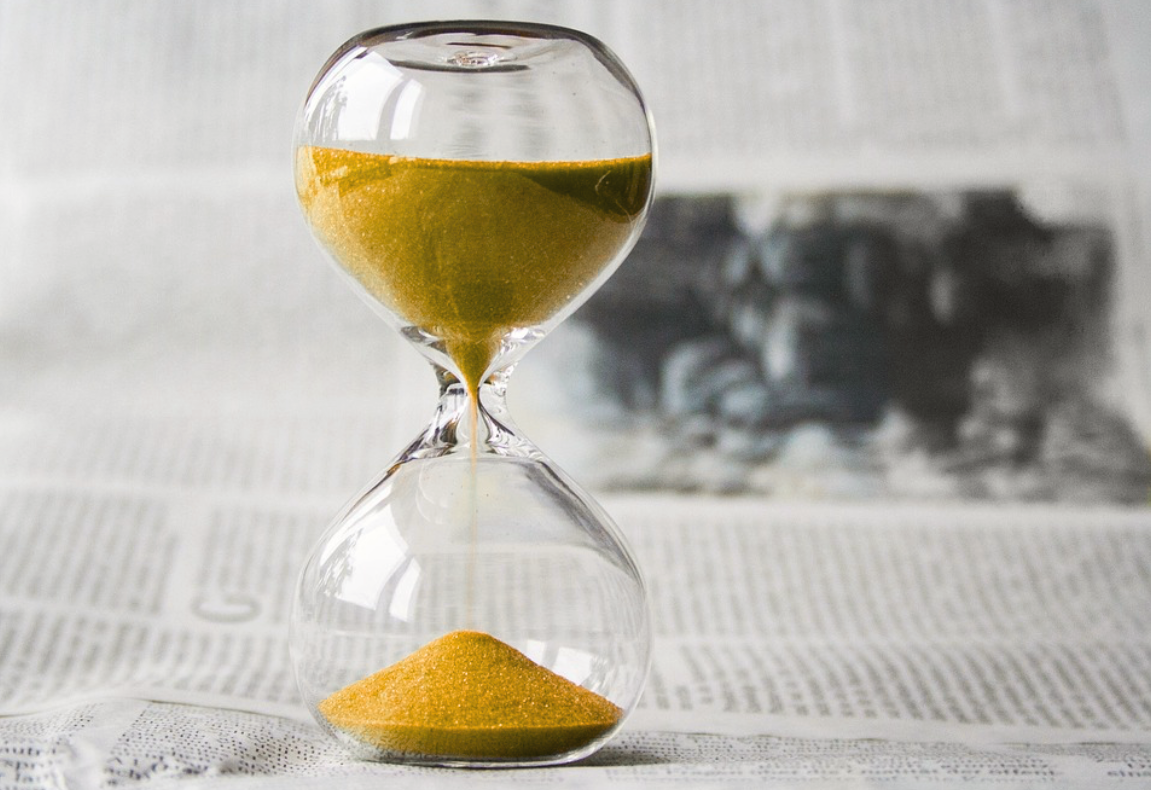 Eisenhower-Prinzip: Sanduhr mit gelben Sand auf Zeitungspapier