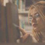 Frau nimmt Buch aus Bücherregal
