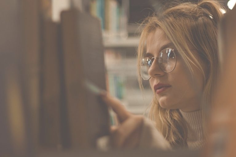 Frau nimmt Buch aus Bücherregal
