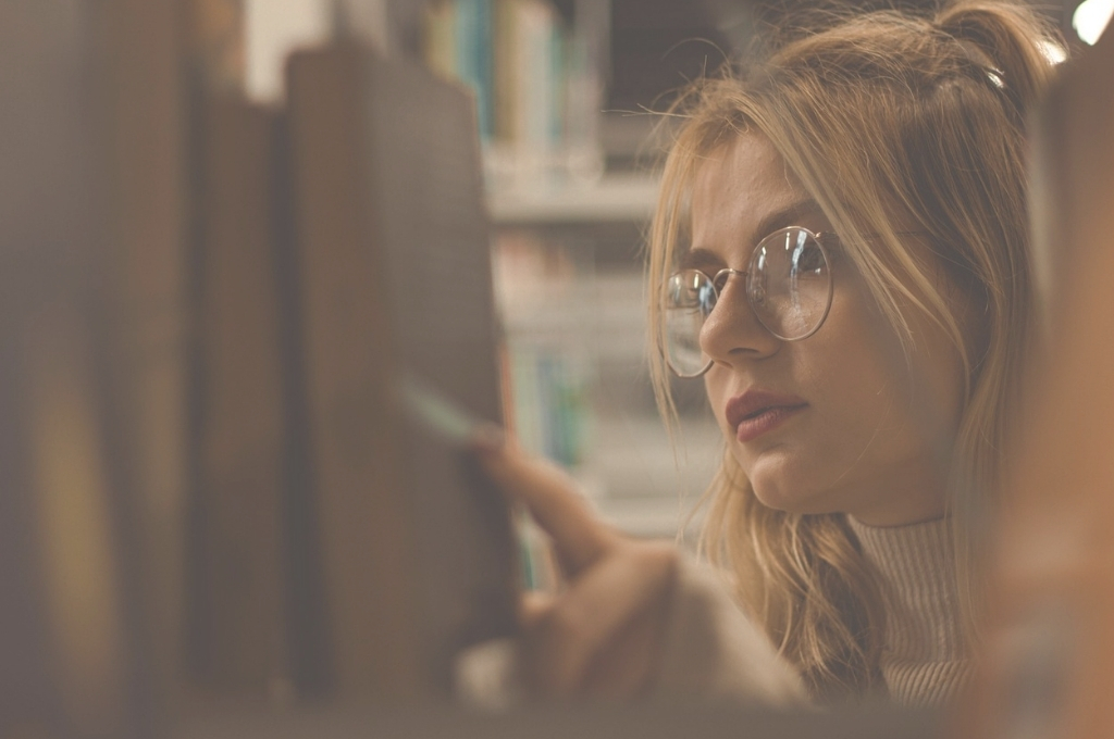 Frau nimmt Buch aus Bücherregal