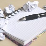 Schreibblock mit Stift und zerknülltem Papier