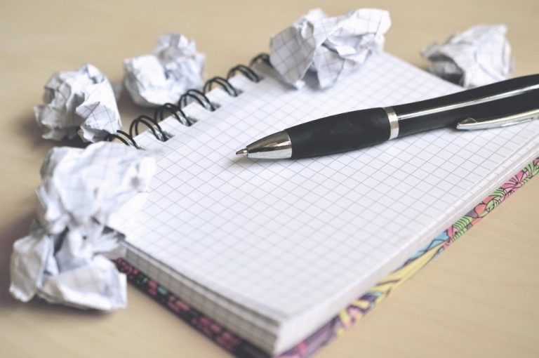 Schreibblock mit Stift und zerknülltem Papier