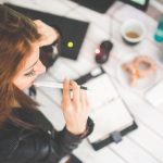 Frau sitzt an Schreibtisch und plant