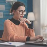 Was ist ein Lektorat? Frau sitzt mit Notizbuch an Laptop