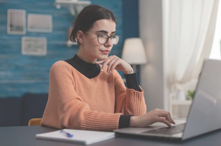 Was ist ein Lektorat? Frau sitzt mit Notizbuch an Laptop